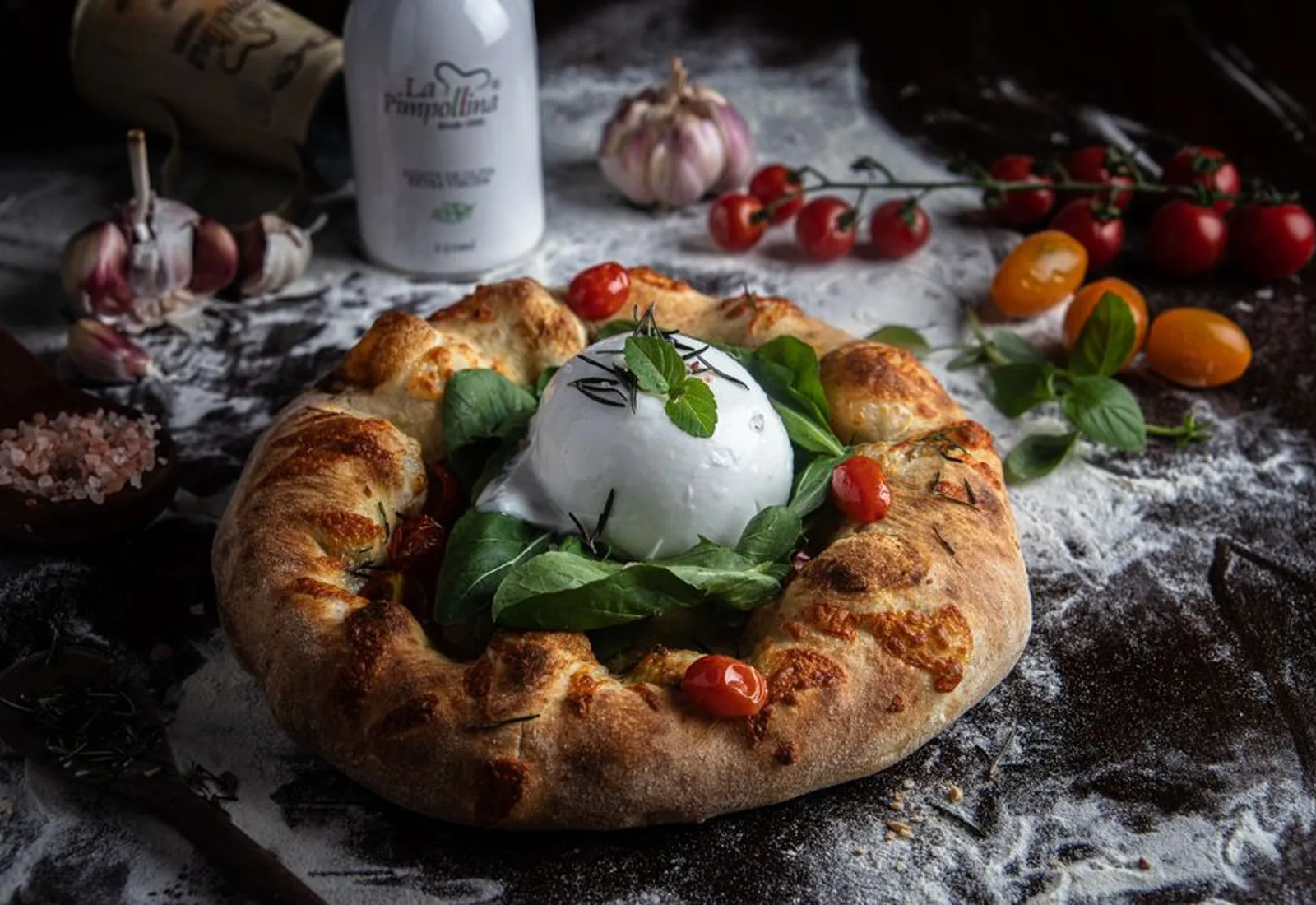 Creamy burrata with prosciutto, tomatoes and basil on a rustic plate