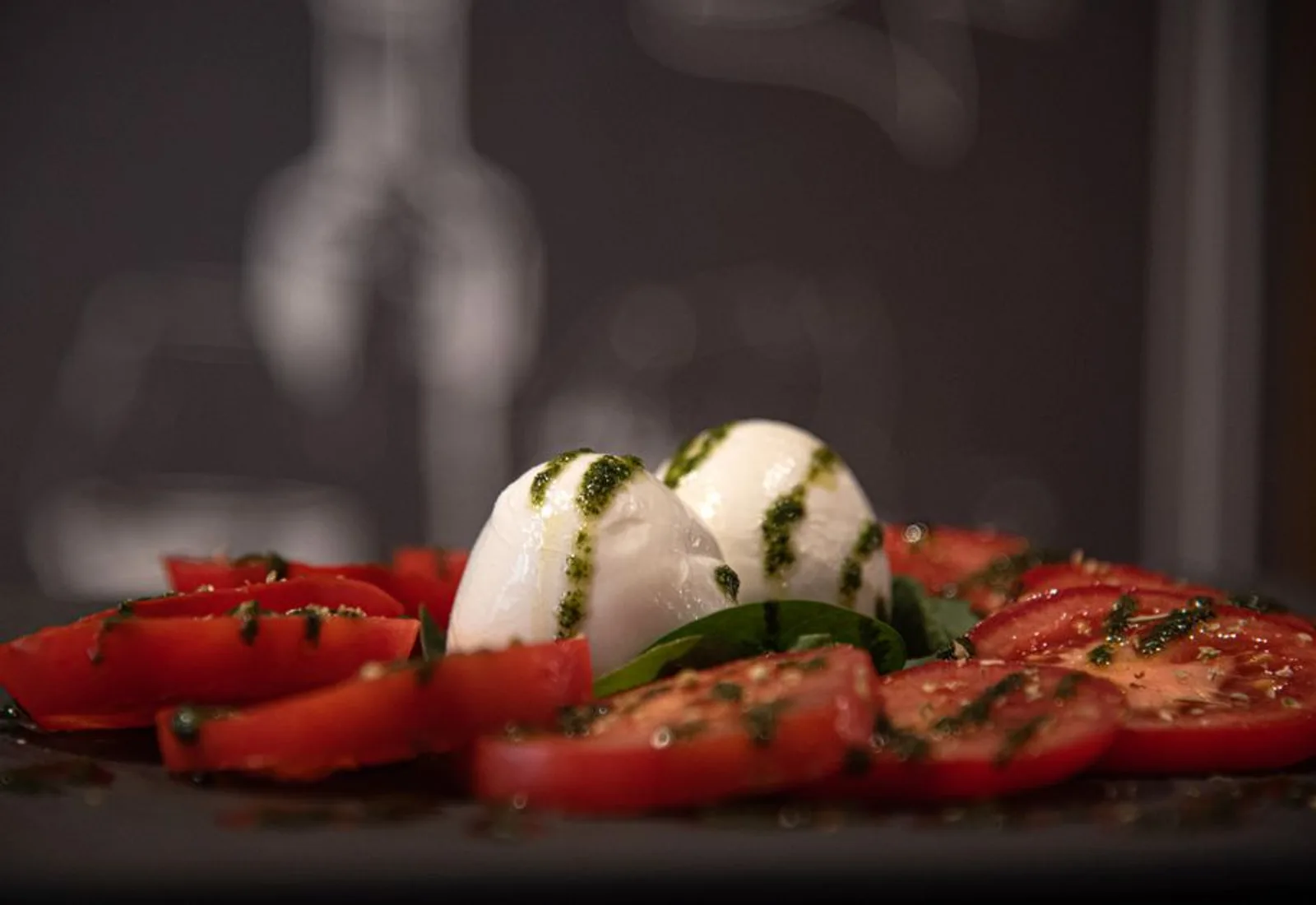 Sliced mozzarella, vine tomatoes and basil, moodily lit