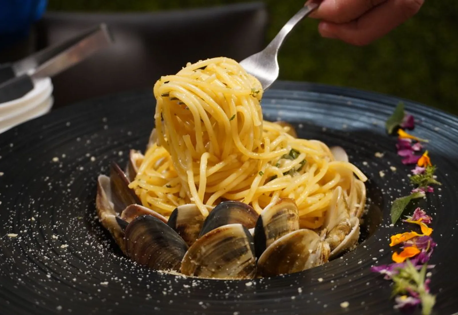 Spaghetti twirled high over littleneck clams, dramatically lit