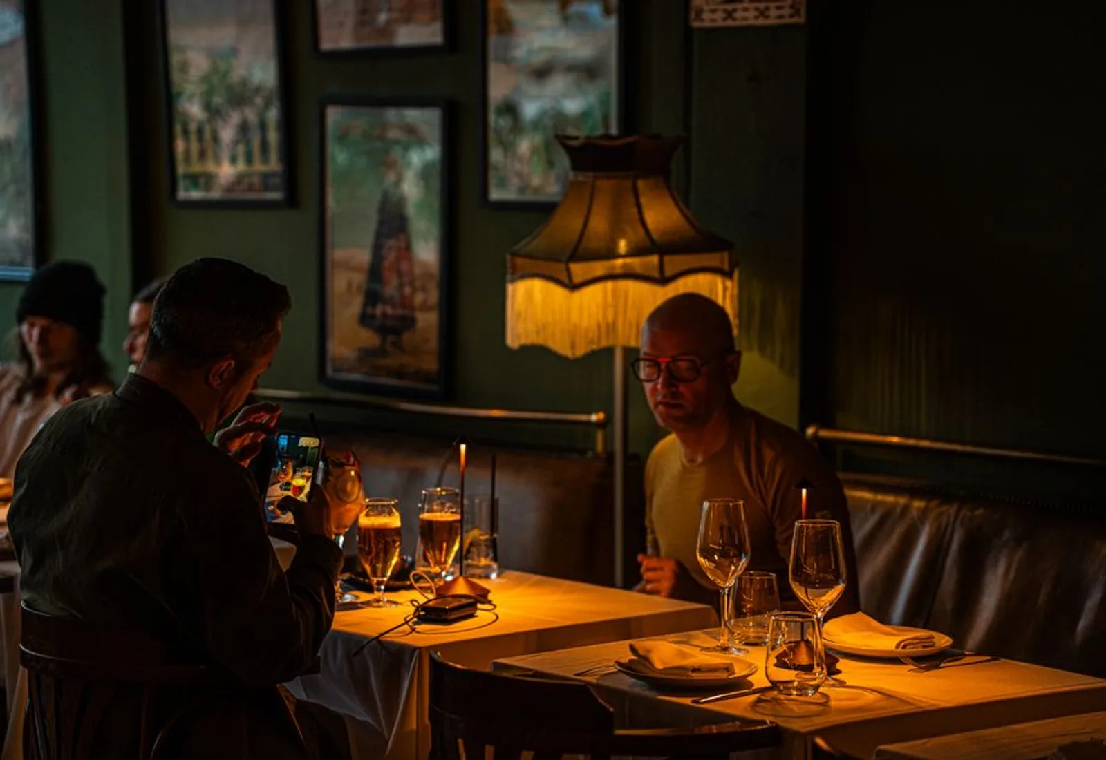 The dining room at night — candlelit tables, warm lamps and diners talking