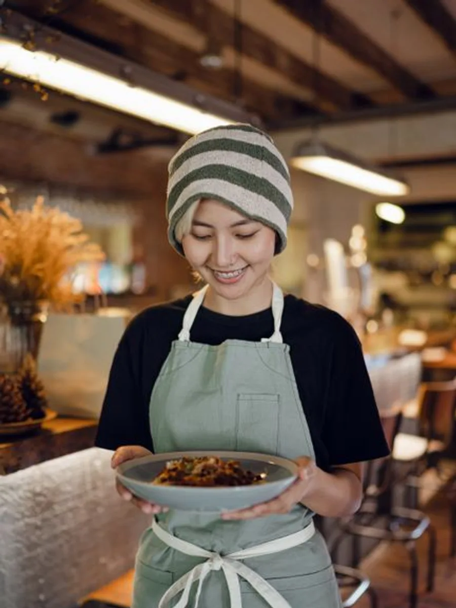 Sofia, front of house, carrying a dish through the room